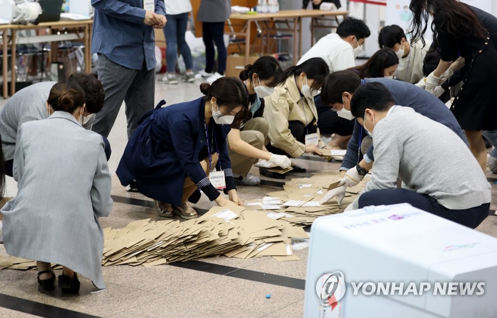 Election officials sort ballots at a polling station in Seoul following the end of the early voting period on April 3, 2021. (Yonhap)