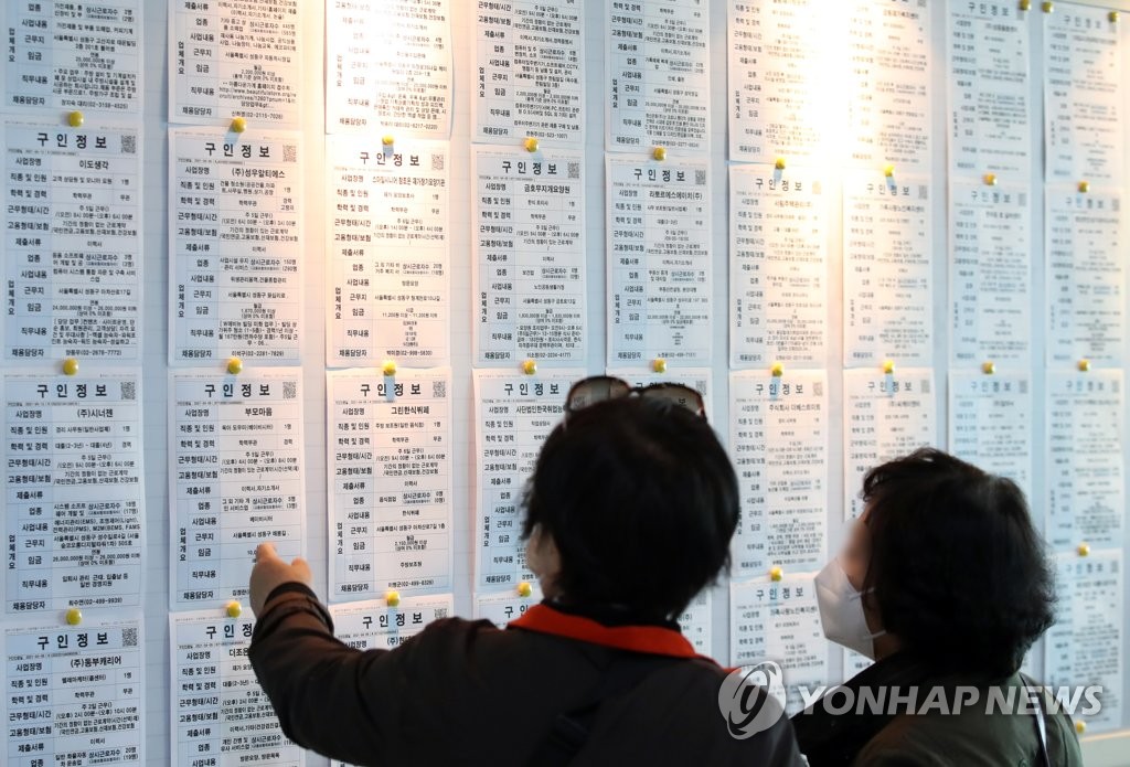 In this April 14, 2021 file photo, citizens look at job information at an employment arrangement center in Seoul. (Yonhap)