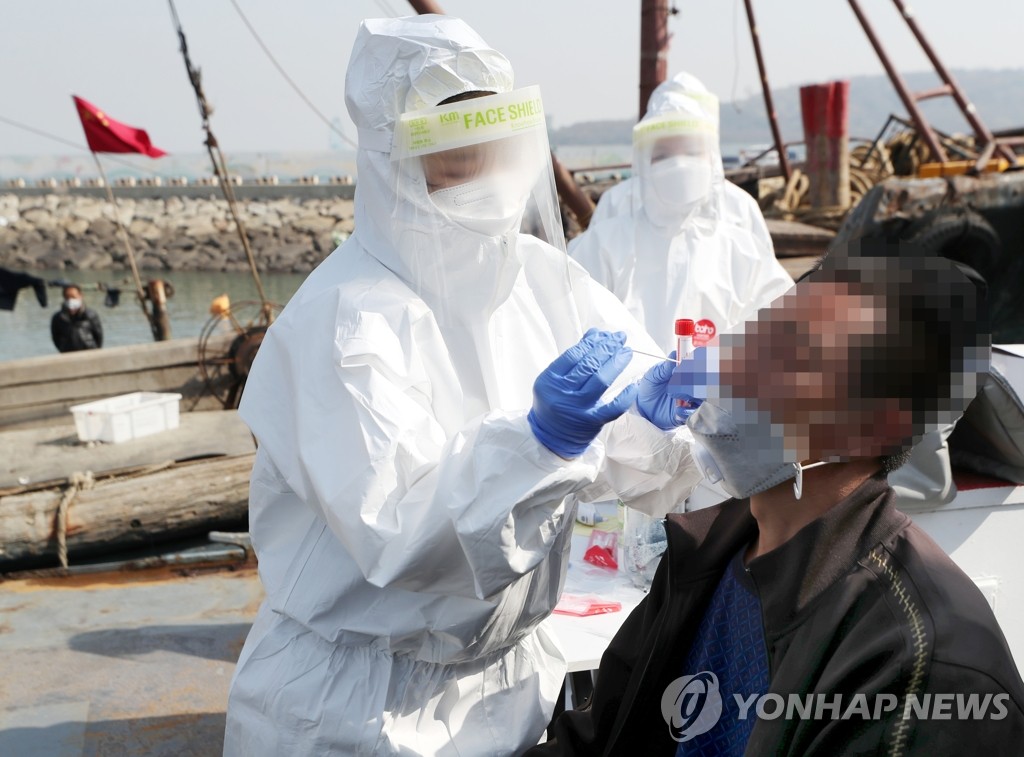 A health worker in a protective suit collects a sample from a Chinese sailor caught fishing illegally inside South Korean waters at a port in Incheon, 40 kilometers west of Seoul, on April 21, 2021. (Yonhap)
