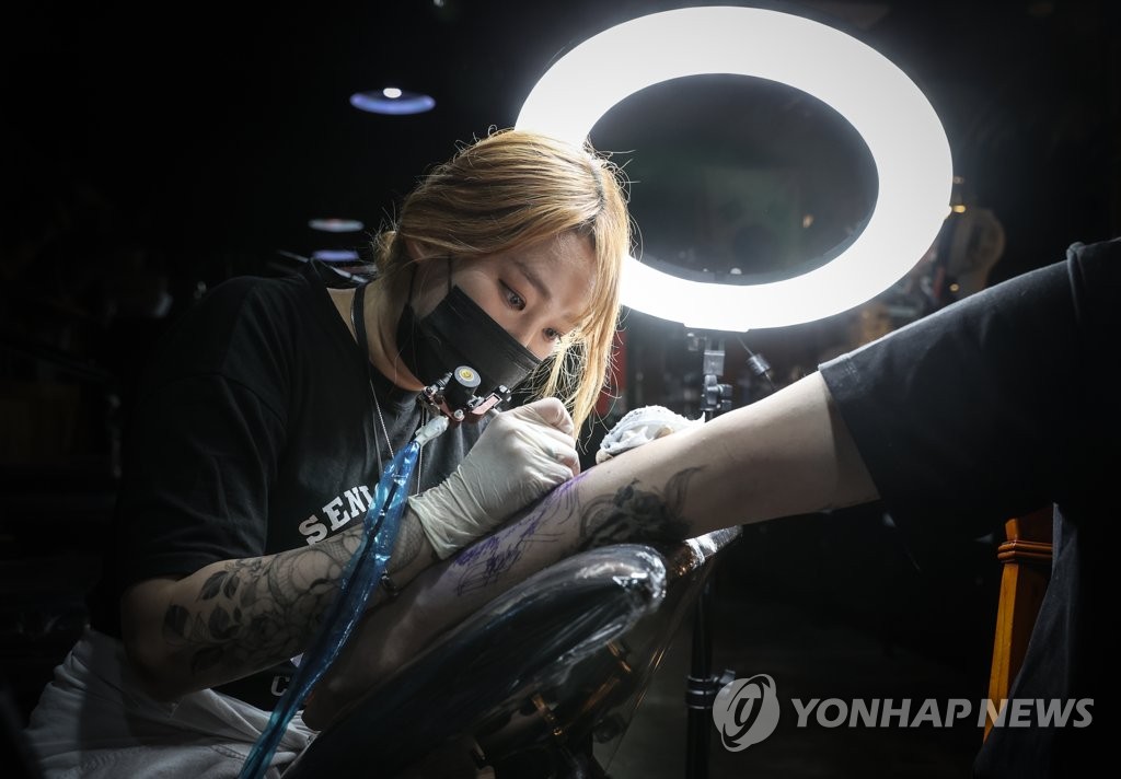 This April 30, 2021, file photo shows a tattooist inking a tattoo on a customer's forearm at a studio in Seoul. (Yonhap)