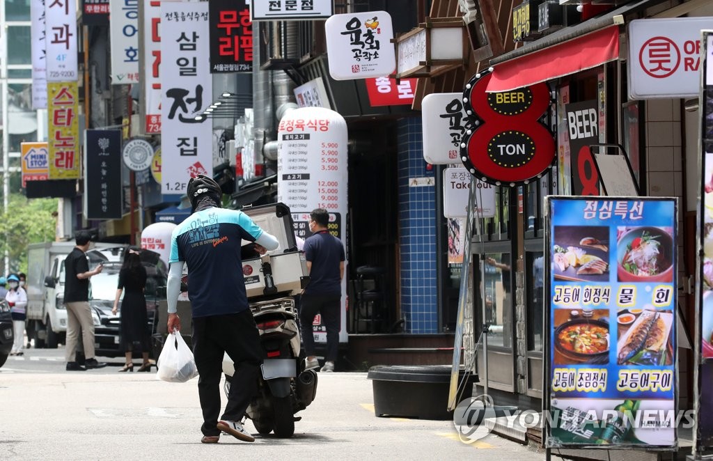 A delivery worker picks up take-out food in central Seoul on July 12, 2021. (Yonhap)