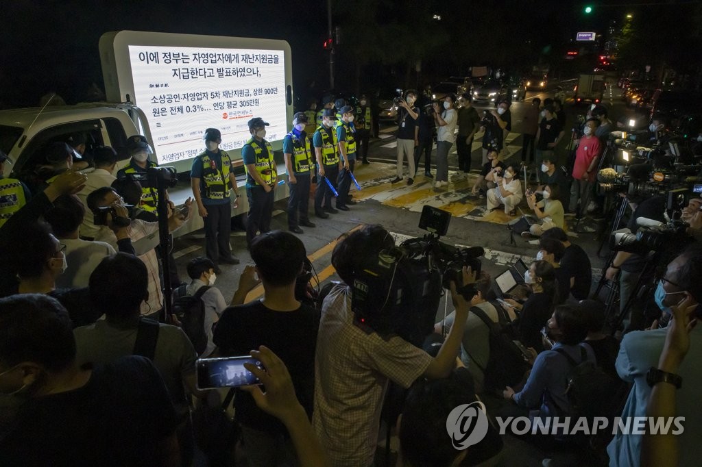 Police and the press are gathered at a protest by small business owners against the government's COVID-19 restrictions near Yeouido Park, western Seoul, on July 14, 2021. (Yonhap)