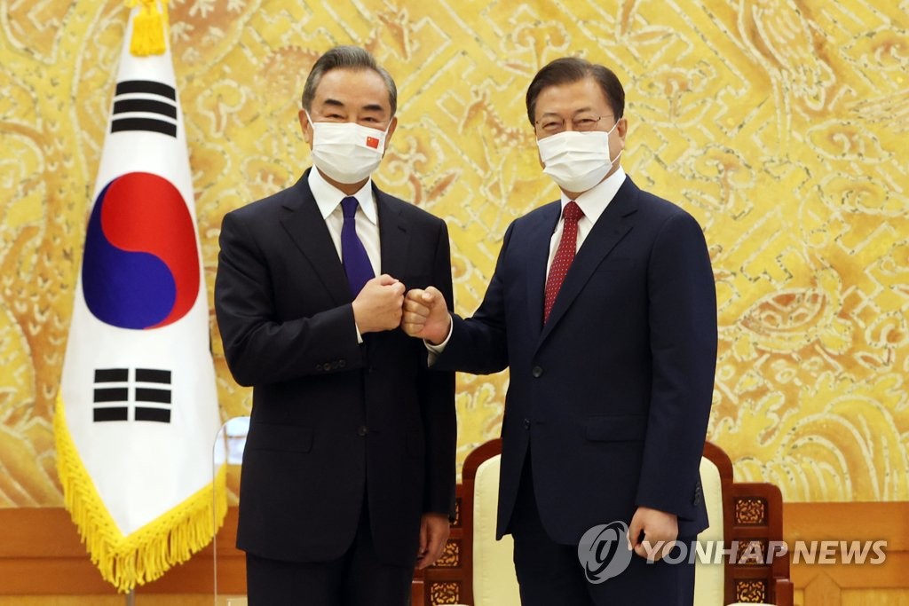 El presidente surcoreano, Moon Jae-in (dcha.), posa para una fotografía, chocando los puños con el ministro de Asuntos Exteriores de China, Wang Yi, el 15 de septiembre de 2021, en la oficina presidencial, Cheong Wa Dae, en Seúl.