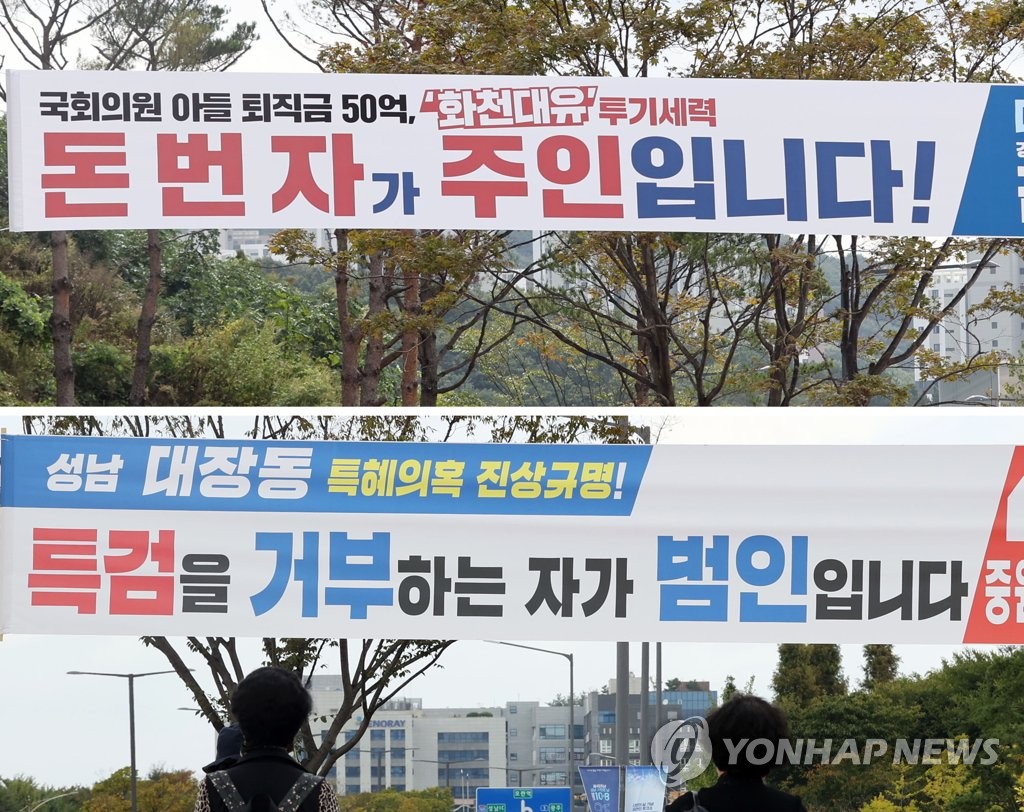 This Oct. 5, 2021, composite file photo shows banners put up by the ruling Democratic Party (DP) and the main opposition People Power Party (PPP), respectively, near the city hall building in Seongnam, just south of Seoul, each accusing politicians of the other party of being involved in a controversial land development scandal. The upper photo shows the banner hung by the DP and the bottom one the one by the PPP. (Yonhap)