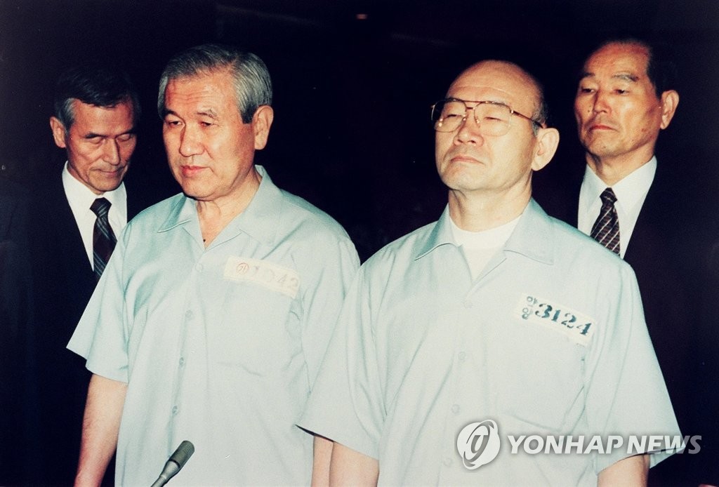 Former President Chun Doo-hwan (R) and his successor Roh Tae-woo stand in prison uniforms in a courtroom on trial on numerous counts of insurgency, graft and murder in Seoul, in this file photo dated Aug. 26, 1996. (Yonhap)