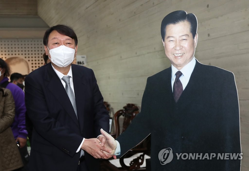 Yoon Seok-youl, the presidential nominee of the main opposition People Power Party, holds the hand of a cutout of late former President Kim Dae-jung at the Kim Dae Jung Nobel Peace Prize Memorial in the southwestern city of Mokpo on Nov. 11, 2021. (Yonhap)