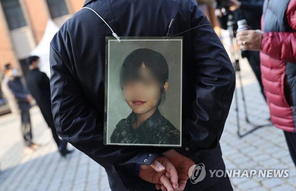 This photo, taken Nov. 25, 2021, shows the father of a deceased Air Force noncommissioned officer holding a picture of his daughter during a protest in Seoul. She took her own life in May after being sexually harassed by a colleague. (Yonhap)