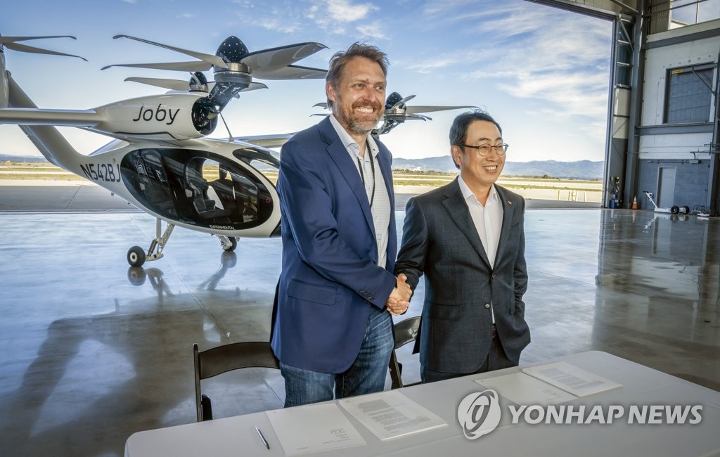 This photo, provided by SK Telecom Co. (SKT), shows SKT CEO Ryu Young-sang (R) posing with JoeBen Bevirt, head of Joby Aviation, during a visit to the urban air mobility (UAM) manufacturer in California last month. SKT, South Korea's biggest mobile carrier, said on Feb. 7, 2022, that the two companies have signed a UAM business accord. (PHOTO NOT FOR SALE) (Yonhap)