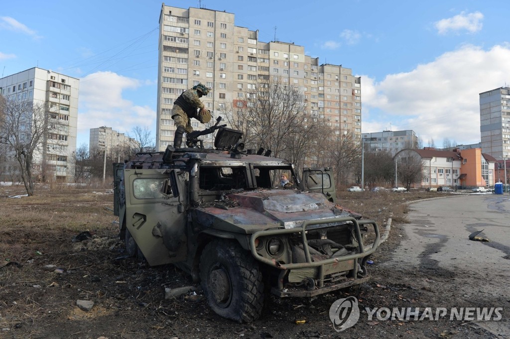 파괴된 러시아 군용차량 살피는 우크라 향토방위군