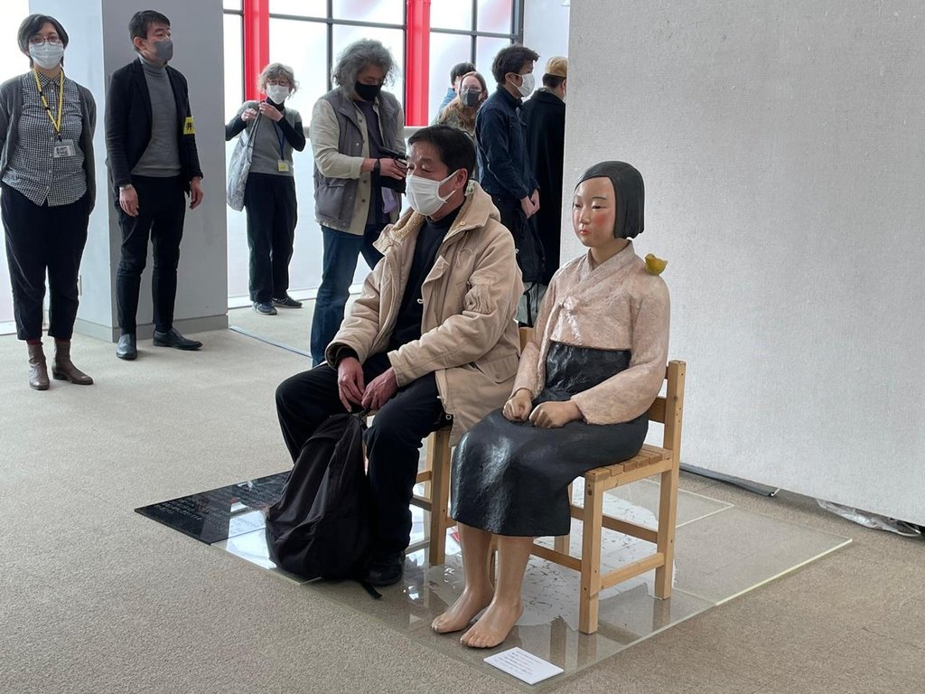 東京・国立で開幕した「表現の不自由展」で、少女像の隣に座る来場客＝２日、東京（聯合ニュース）