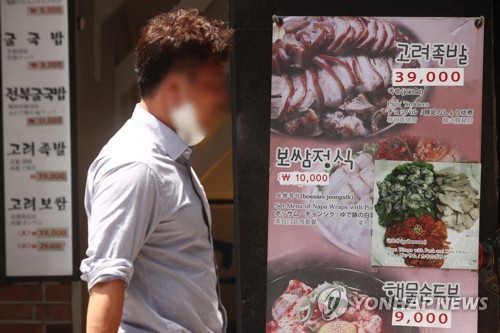 ソウル市内の飲食店では看板の価格表示の上に値上げした価格が貼られている＝（聯合ニュース）