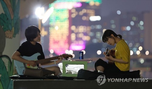 (서울=연합뉴스) 김인철 기자 = 무더운 날씨가 이어지는 5일 오후 서울 영등포구 여의도한강공원에서 시민들이 기타를 치며 더위를 식히고 있다. 2022.7.5 yatoya@yna.co.kr