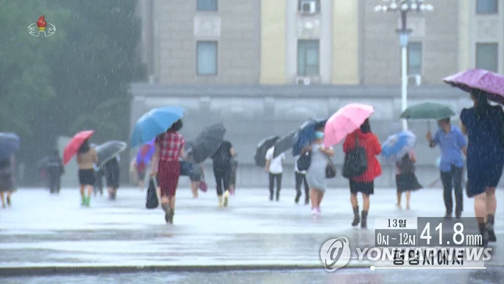 우산으로 비바람 막는 평양 시민들