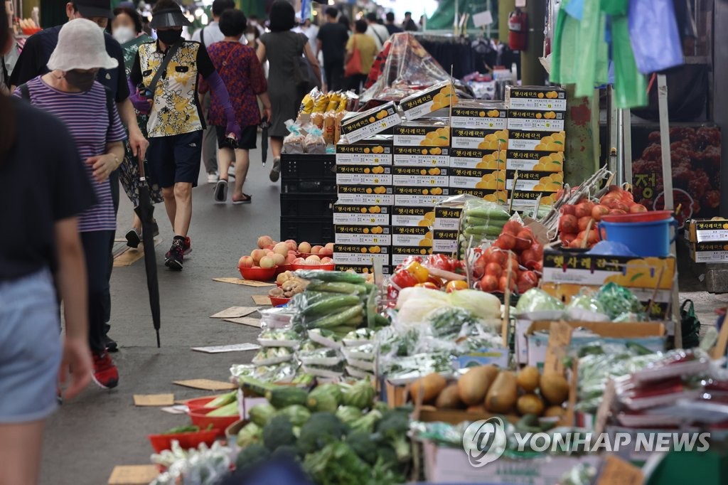 People look at vegetables while grocery shopping at a traditional market in Seoul on Aug. 3, 2022. (Yonhap)