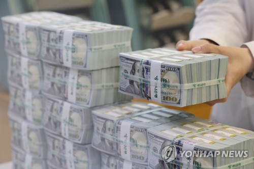 A banker piles U.S. dollar bills at a bank in central Seoul in this file photo taken on Nov. 3, 2022. (Yonhap)