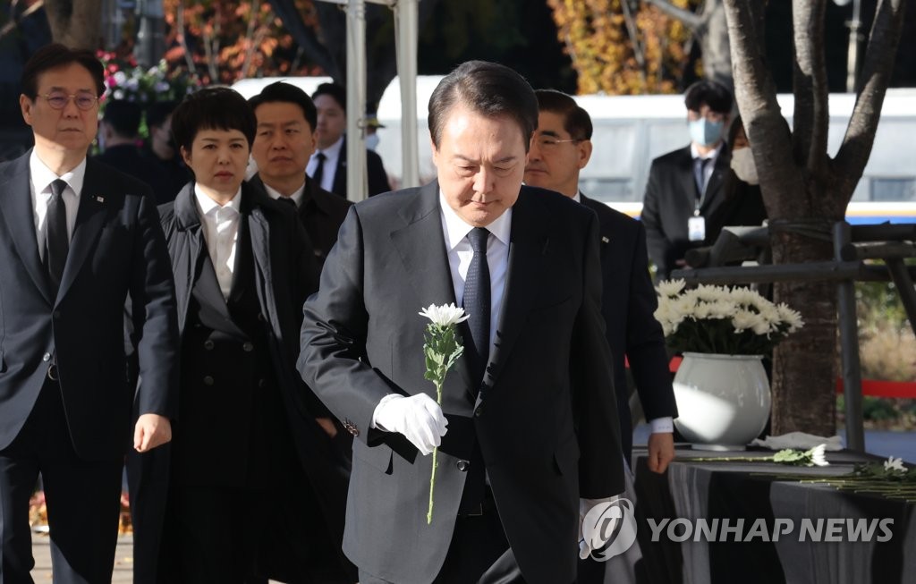 President Yoon Suk-yeol carries a chrysanthemum to a mourning altar for victims of the Halloween crowd crush in front of City Hall in Seoul on Nov. 4, 2022. (Yonhap)