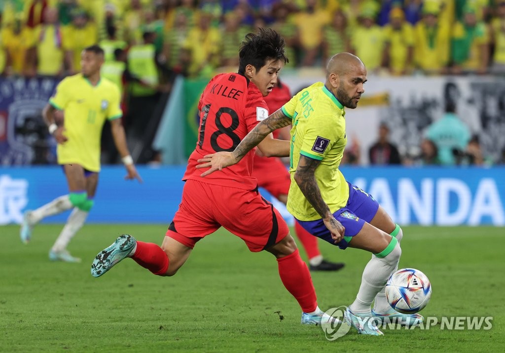 Lee Kang-in of South Korea (L) battles Dani Alves of Brazil for the ball during the countries' round of 16 match at the FIFA World Cup at Stadium 974 in Doha on Dec. 5, 2022. (Yonhap)
