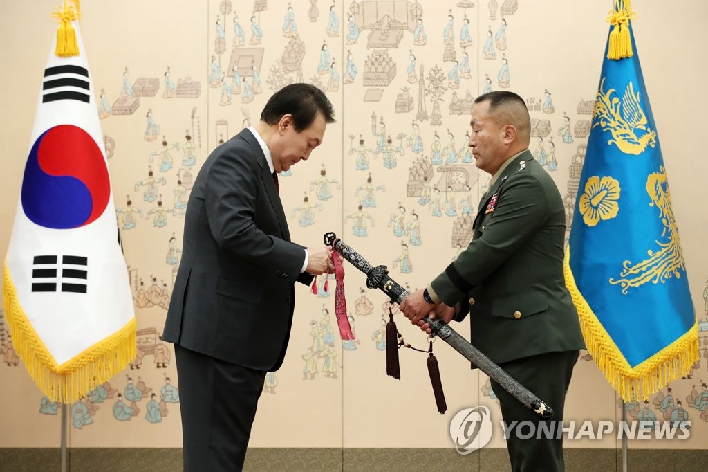 President Yoon Suk-yeol (L) ties a ribbon to the "samjeonggeom" sword of new Marine Corps Commander Kim Gye-hwan at the presidential office in Seoul on Dec. 7, 2022. (Pool photo) (Yonhap)