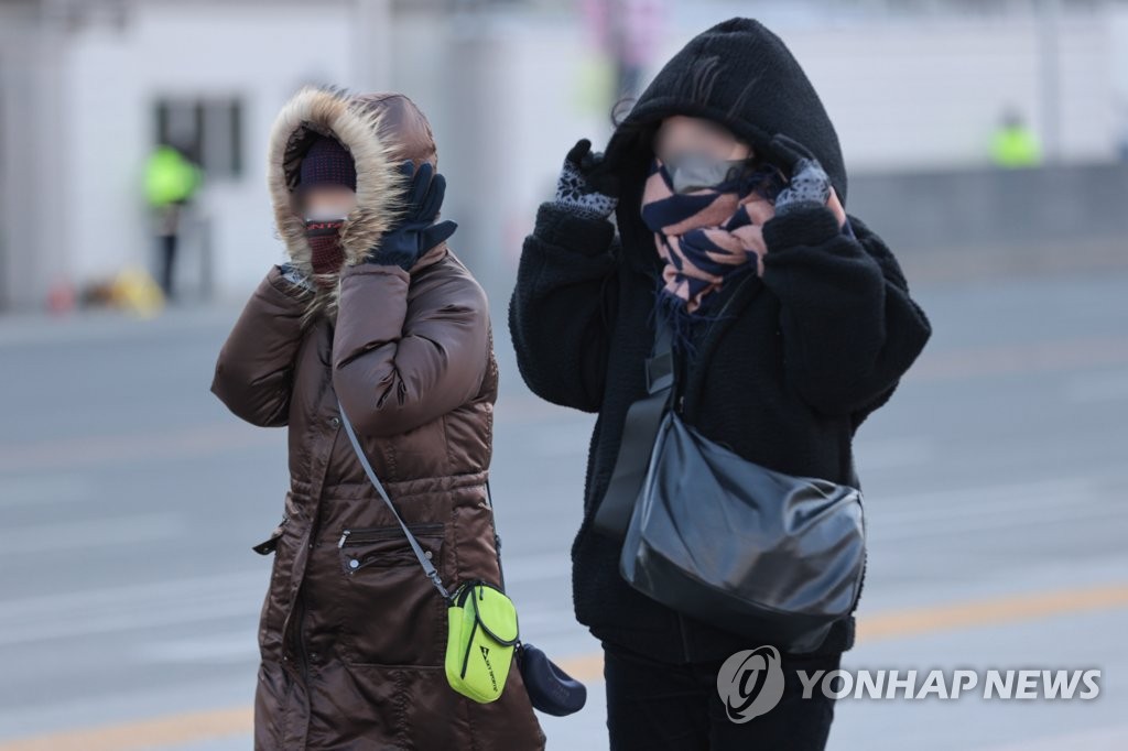 Des personnes vêtues de manteaux épais marchent dans le grand froid sur la place de Gwanghwamun, dans le centre de Séoul, le mardi 24 janvier 2023. 