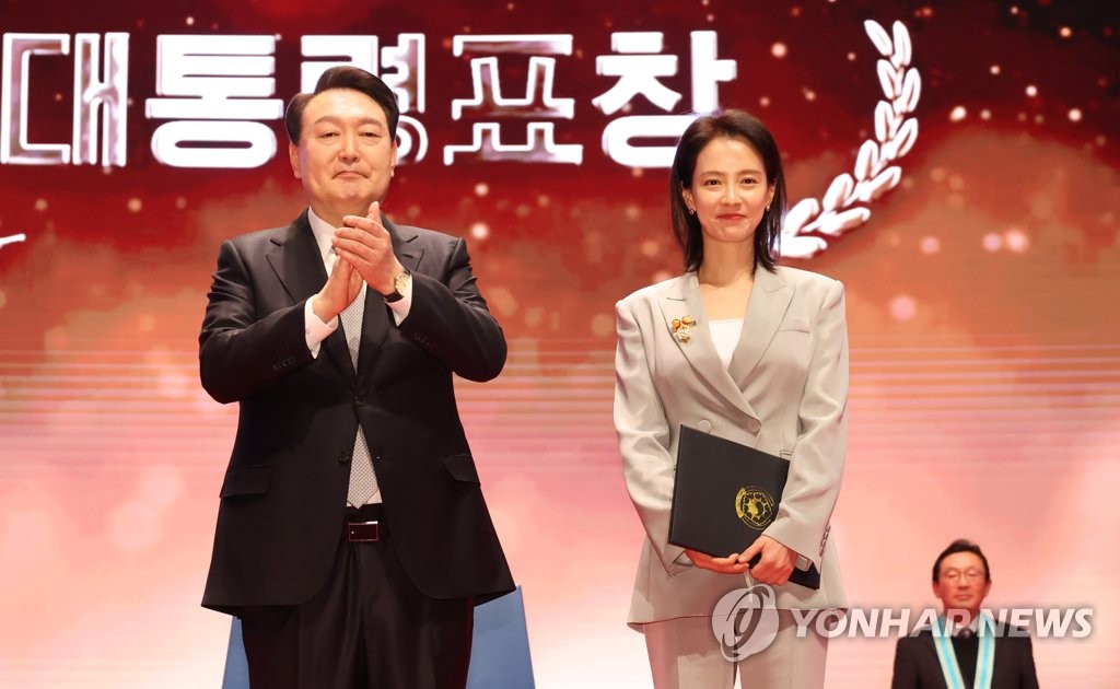 President Yoon Suk Yeol (L) poses for a photo with actress Song Ji-hyo after presenting her with a presidential citation for being an exemplary taxpayer during a ceremony at the COEX exhibition center in Seoul on March 3, 2023, to mark the 57th Taxpayers' Day. (Yonhap)