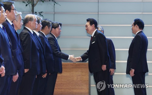 El presidente surcoreano, Yoon Suk Yeol (segundo por la dcha.), saluda, el 16 de marzo de 2023, con un apretón de manos a los miembros del Gabinete japonés, tras la inspección de una guardia de honor, previo a su cumbre bilateral con el primer ministro, Fumio Kishida, en la residencia de este último, en Tokio.