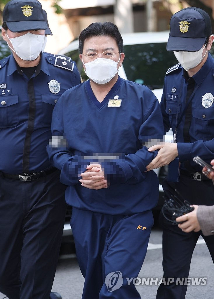 Ra Deok-yeon (C), head of an unregistered investment consulting firm, is taken to the Seoul Southern District Court in the capital on May 11, 2023, to attend a hearing to review the legality of his detention on charges of large-scale stock manipulation that rocked the local financial markets. Ra's firm was at the center of the recent collapse of the stock prices of nine companies, including energy firm Samchully Co. and Seoul City Gas Co. (Yonhap)