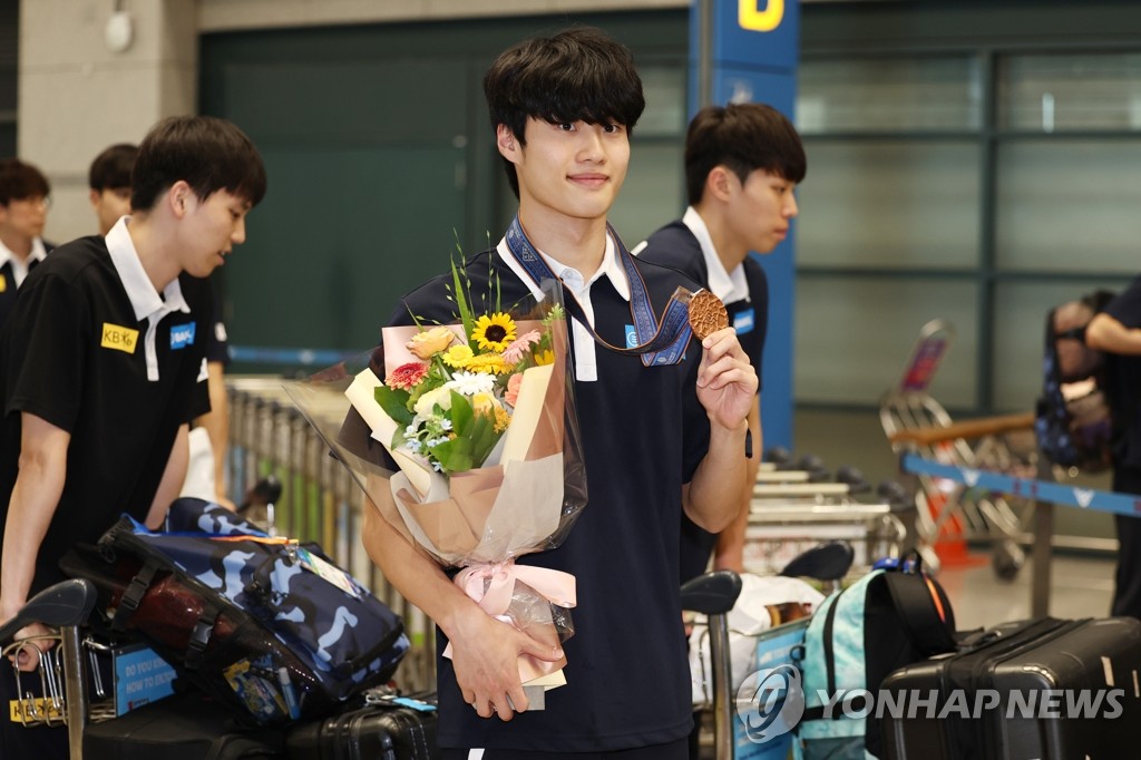 South Korean swimmer Hwang Sun-woo (C) holds up his bronze medal won from the men's 200-meter freestyle at the World Aquatics Championships in Fukuoka, Japan, upon arriving at Incheon International Airport, west of Seoul, on July 31, 2023. (Yonhap)