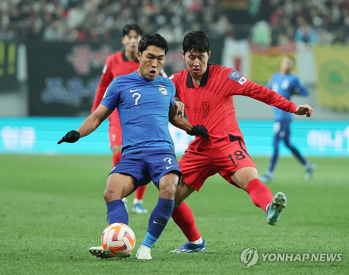 Lee Kang-in of South Korea (R) battles Song Ui-young of Singapore for the ball during the teams' Group C match in the second round of the Asian World Cup qualification tournament at Seoul World Cup Stadium in Seoul on Nov. 16, 2023. (Yonhap)