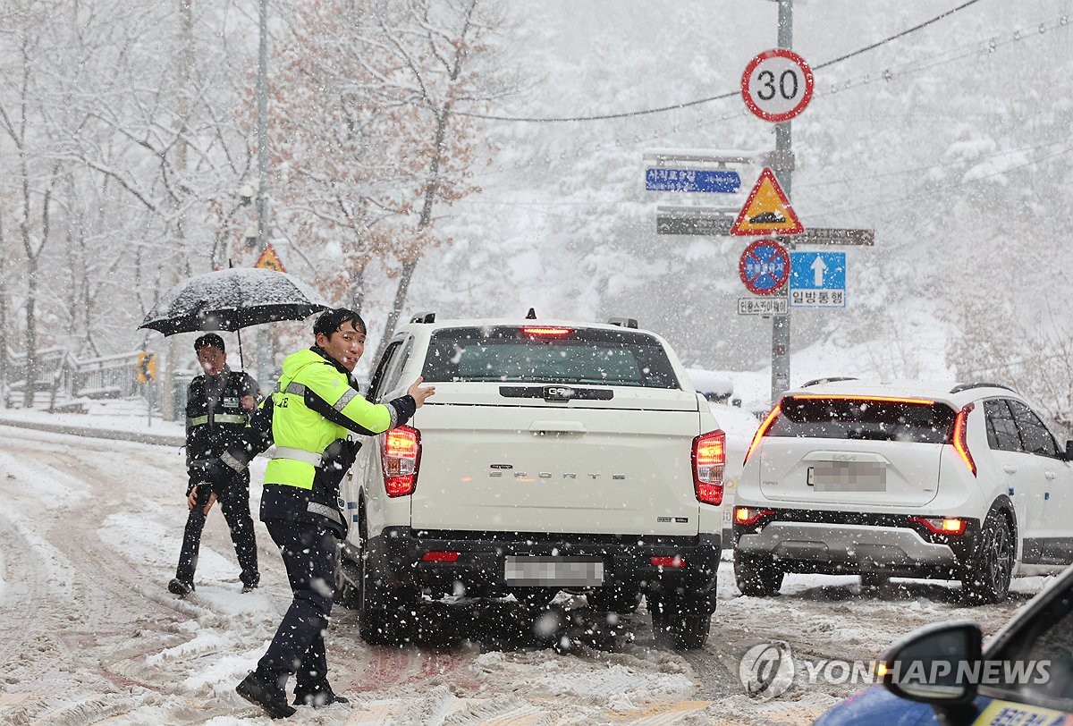 Los agentes de tráfico restringen el acceso a una carretera en el centro de Seúl, ya que está en vigor un aviso de fuertes nevadas en toda la capital el 30 de diciembre de 2023. (Yonhap)