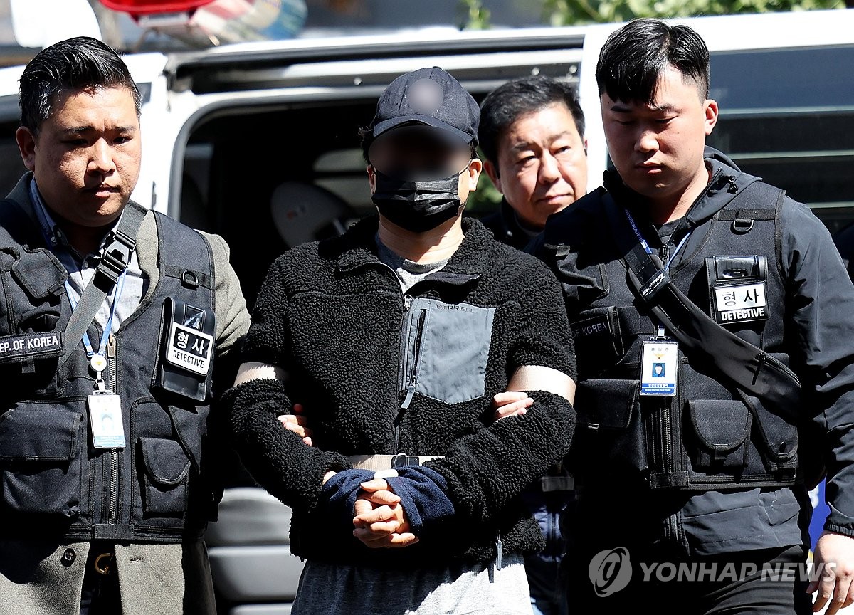 This file photo shows police officers escorting a YouTuber accused of installing spy cameras at 40 early voting stations ahead of the April 10, 2024, parliamentary elections. (Yonhap)