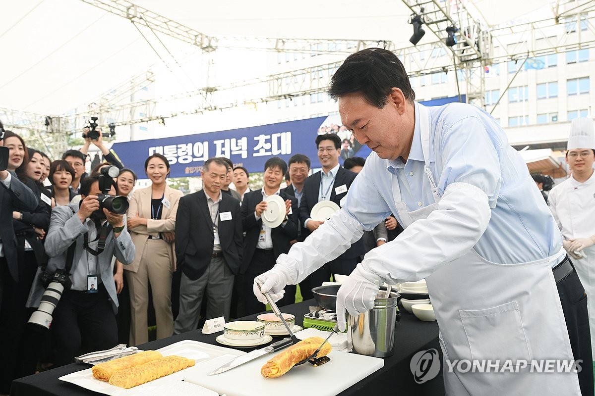 El presidente Yoon Suk Yeol cocina rollitos de huevo durante una cena con periodistas en el césped frente a la oficina presidencial el 24 de mayo de 2024, en esta fotografía proporcionada por su oficina.  (FOTO NO EN VENTA) (Yonhap)