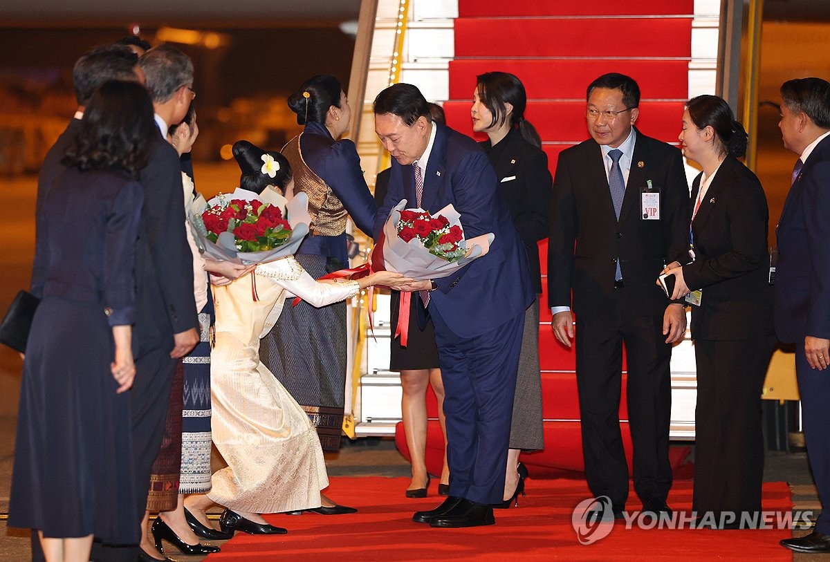 El presidente Yoon Suk Yeol (centro) recibe un ramo de flores a su llegada al aeropuerto internacional Wattay en Vientiane, Laos, el 9 de octubre de 2024. (Yonhap)