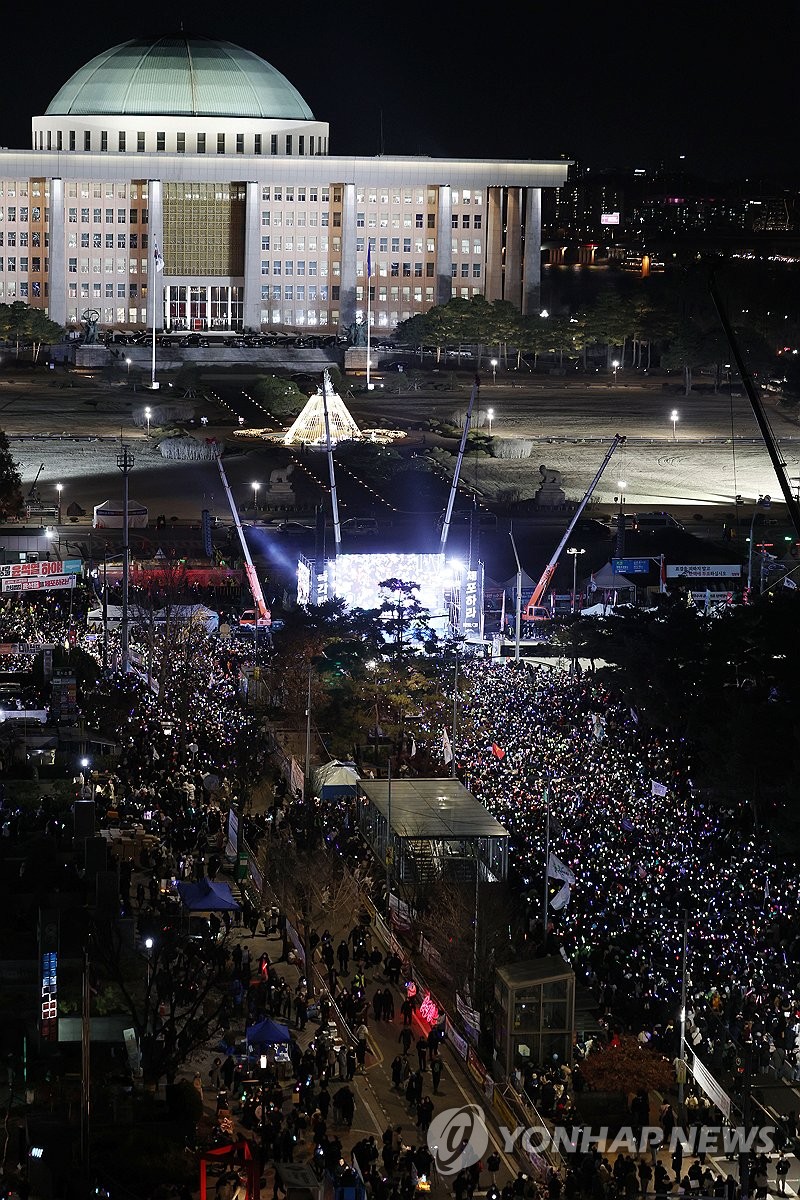 Los manifestantes se reúnen cerca de la Asamblea Nacional en Seúl el 14 de diciembre de 2024, celebrando la aprobación de una moción de juicio político contra el presidente Yoon Suk Yeol. (Yonhap)